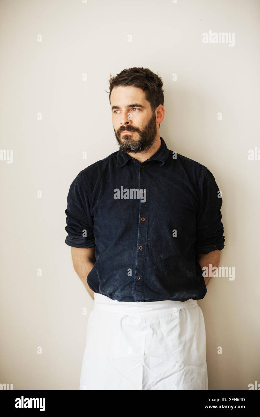 Half length portrait of a bearded man wearing a white apron. Stock Photo