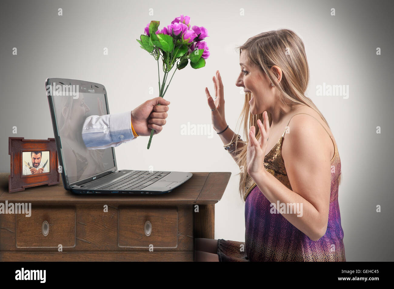 Woman is surprised when a hand holding a bouquet of flowers sticks out the  monitor of laptop she is using Stock Photo - Alamy