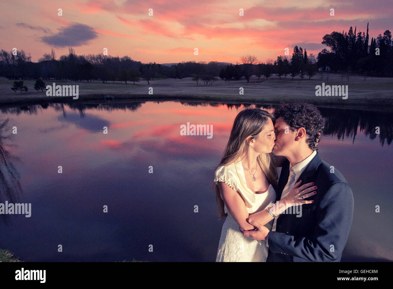 Bride and groom kiss under a spectacular sunset sky Stock Photo - Alamy