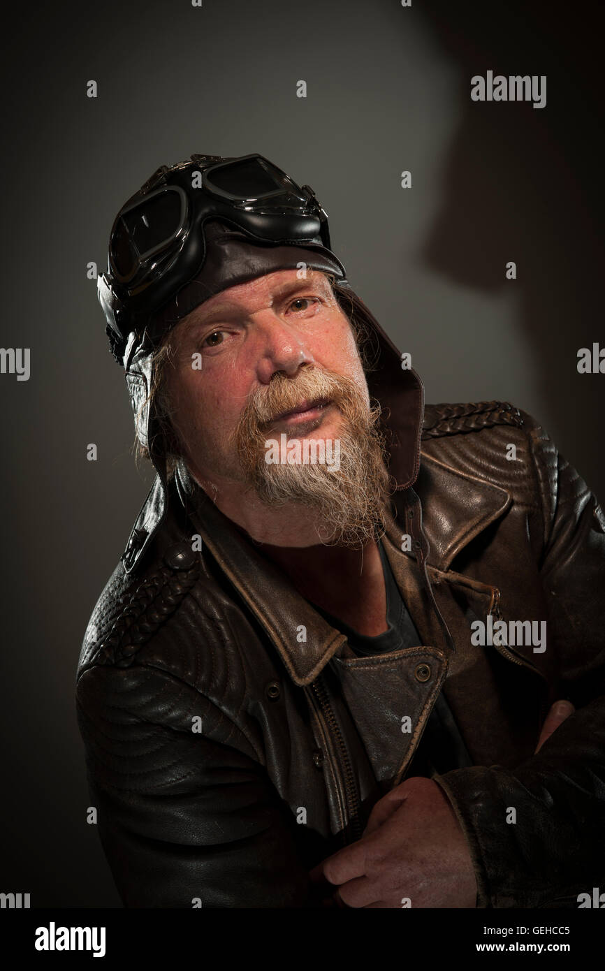 side head and shoulders portrait of older man with a full beard, leather jacket and goggles seriously into the camera Stock Photo