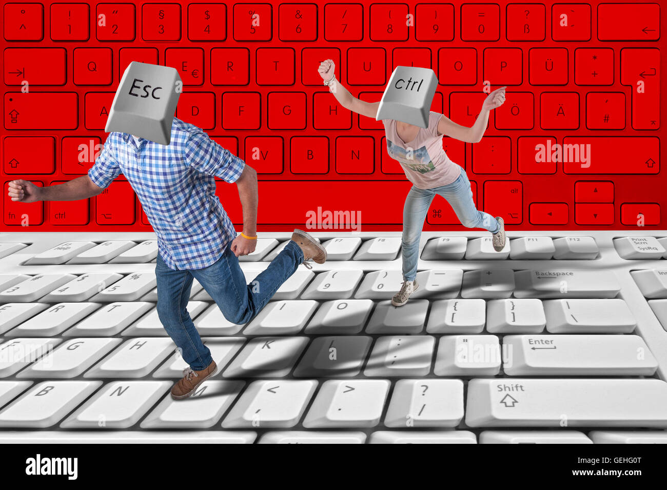 Woman with a control key as a head chases a man with a escape key as a head with a big keyboard on the floor Stock Photo