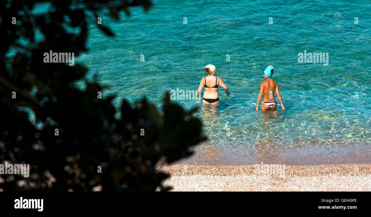 Petrovac, Montenegro - July 12, 2016: Two young women with different skin type entering the water Stock Photo