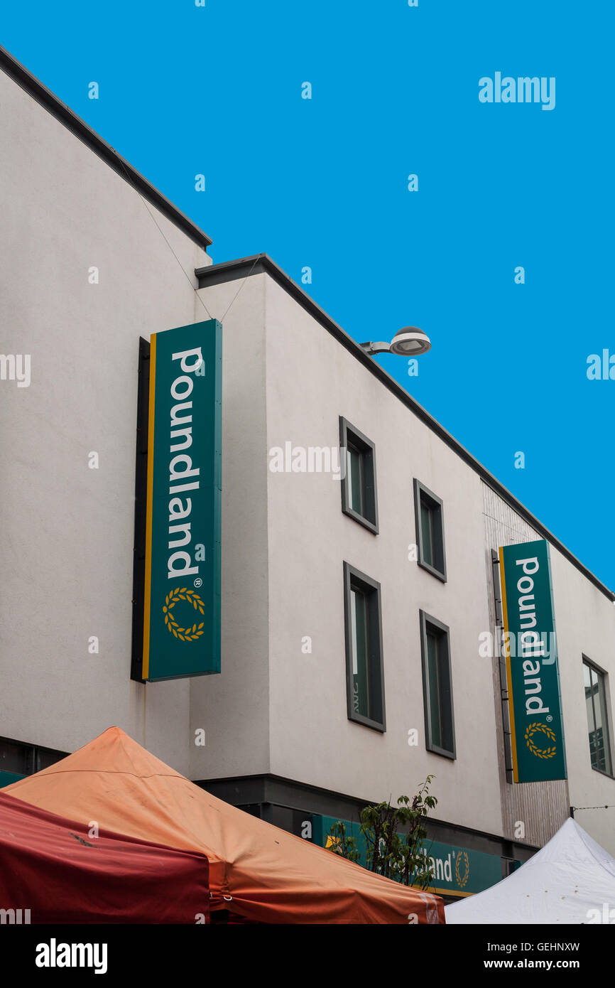 SAINT AUSTELL, CORNWALL, UK - JULY 9, 2016: Poundland store sign on white wall with blue sky. Saint Austell high street shop. Stock Photo