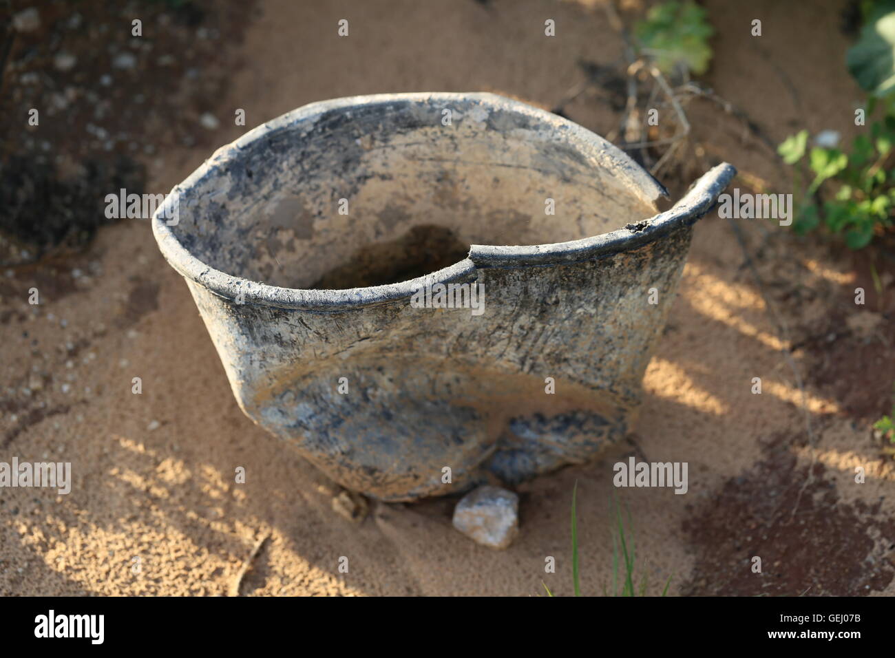 Empty Broken Bucket. Useless broken bucket on the ground in a construction  site Stock Photo - Alamy