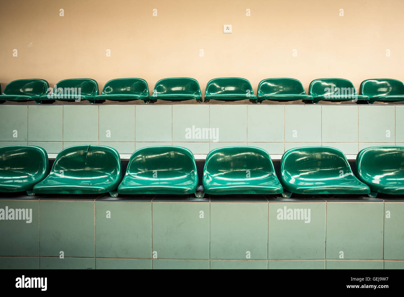 Two rows of empty green seats in a sports hall Stock Photo
