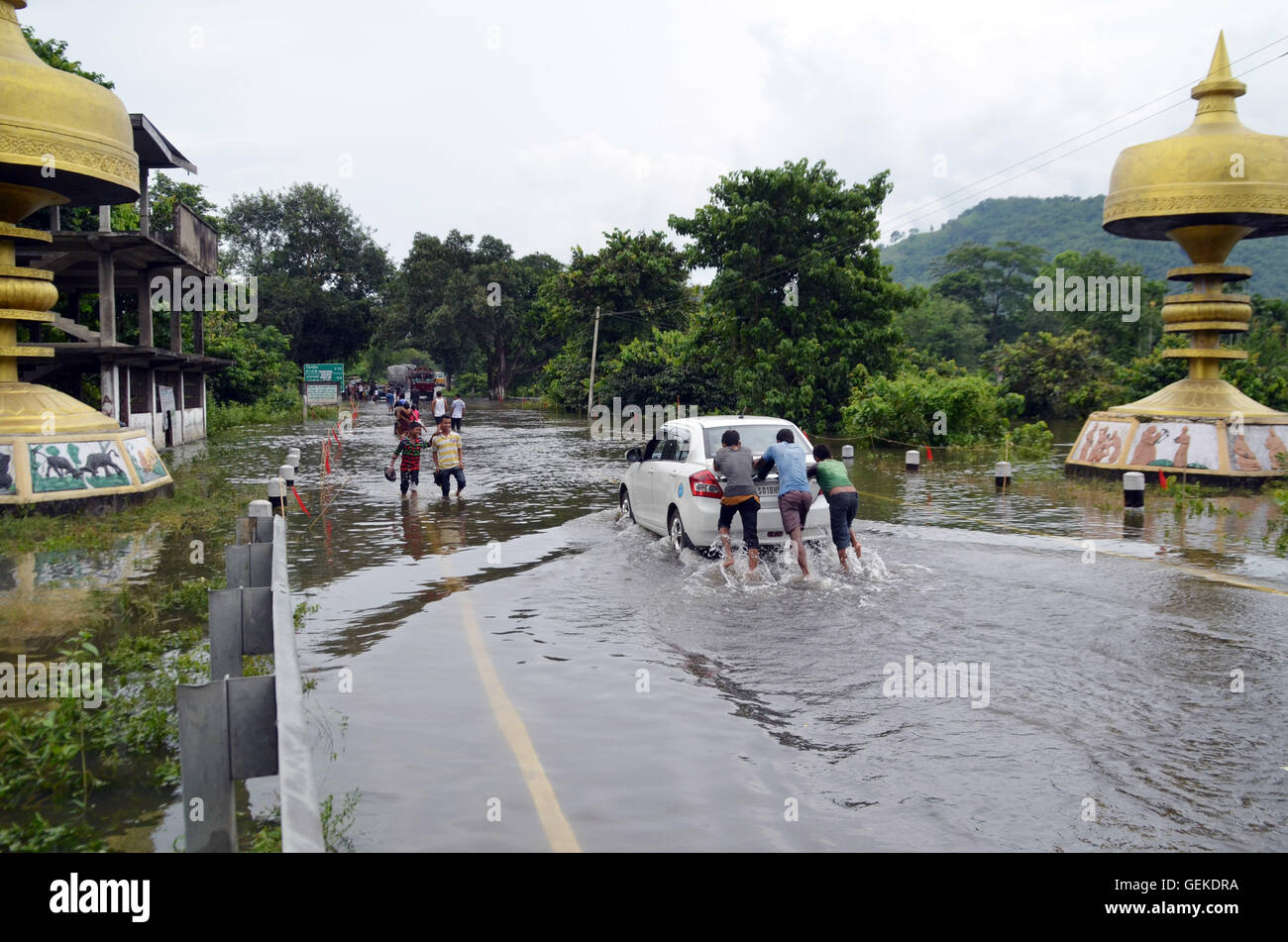 Nagaon, Assam, India. 27th July, 2016. Vehicle and people crossing through submerged National Highway 37 due to heavy flood in Bagori Village near Kaziranga National Park ,some 200 kms away from Guwahati, the capital city of North eastern Indian state Assam on Wednesday. The rapid rising of flood water has caused loss to life and property in Assam. Credit:  DIGANTA TALUKDAR/Alamy Live News Stock Photo