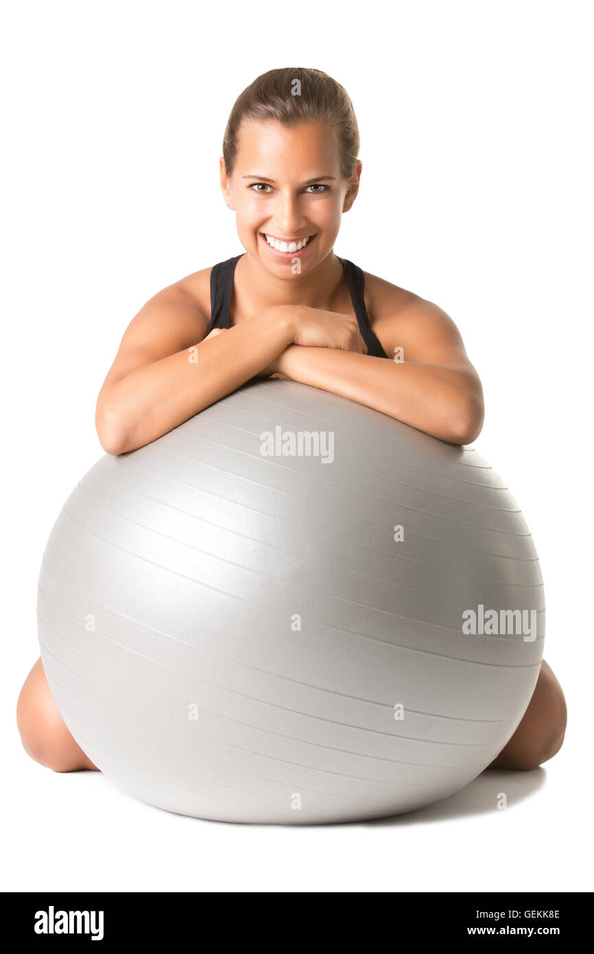 Fit woman sitting and holding a pilates ball on the floor, isolated in white Stock Photo