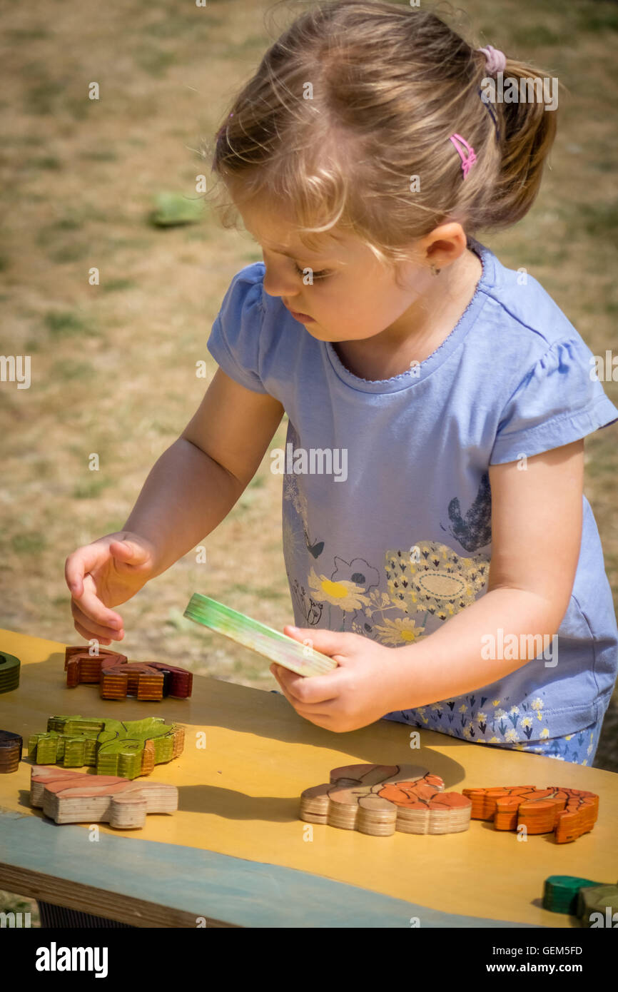 Little girl playing with the wooden puzzle in the playground Stock ...