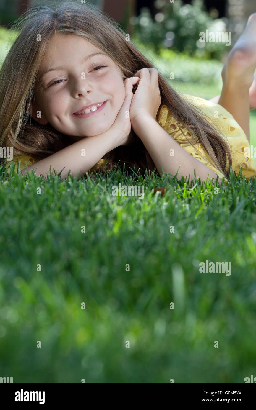 portrait of little girl laying on the grass in summer environment Stock ...