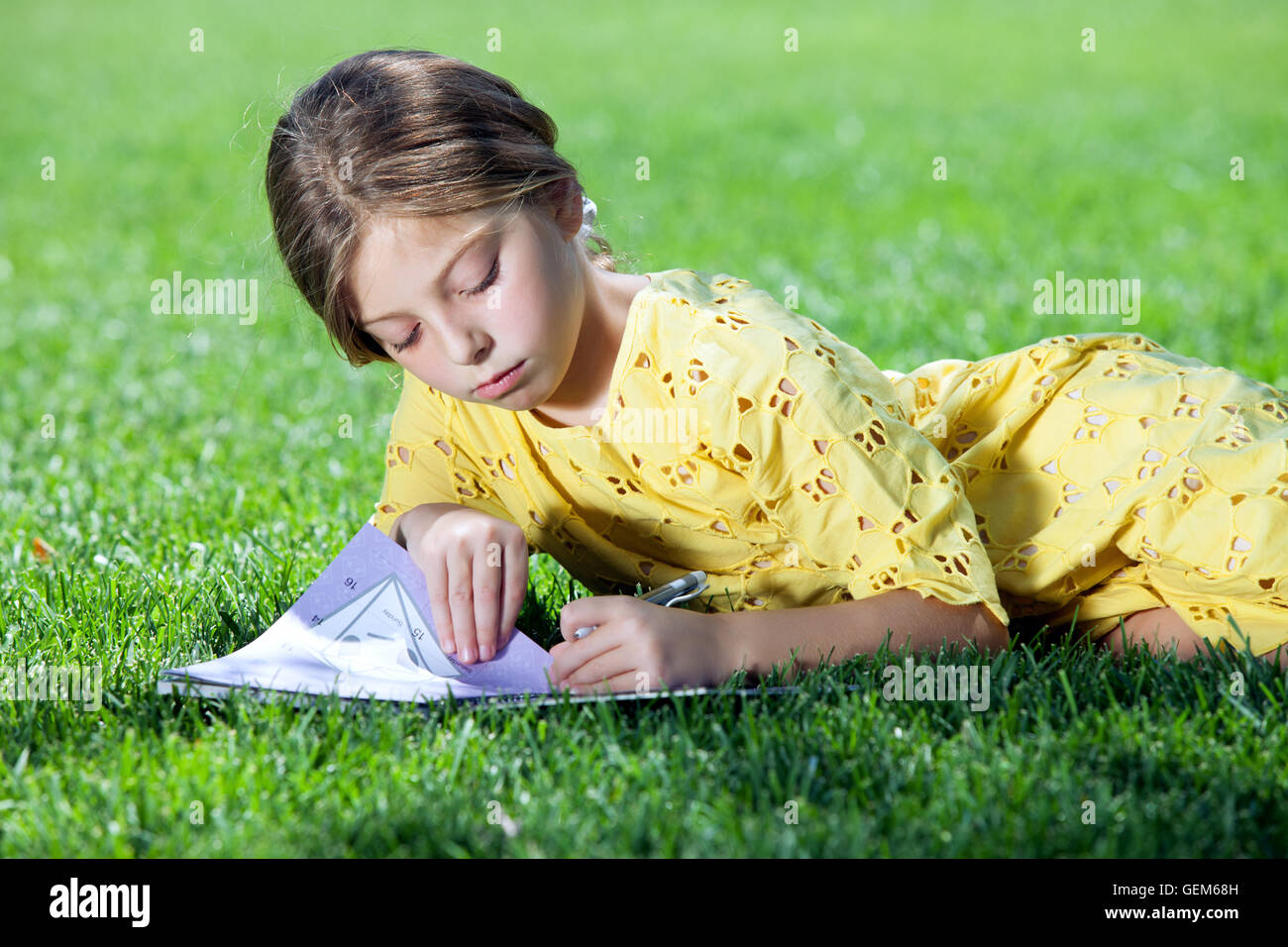 portrait of little girl studying on the grass in summer environment ...