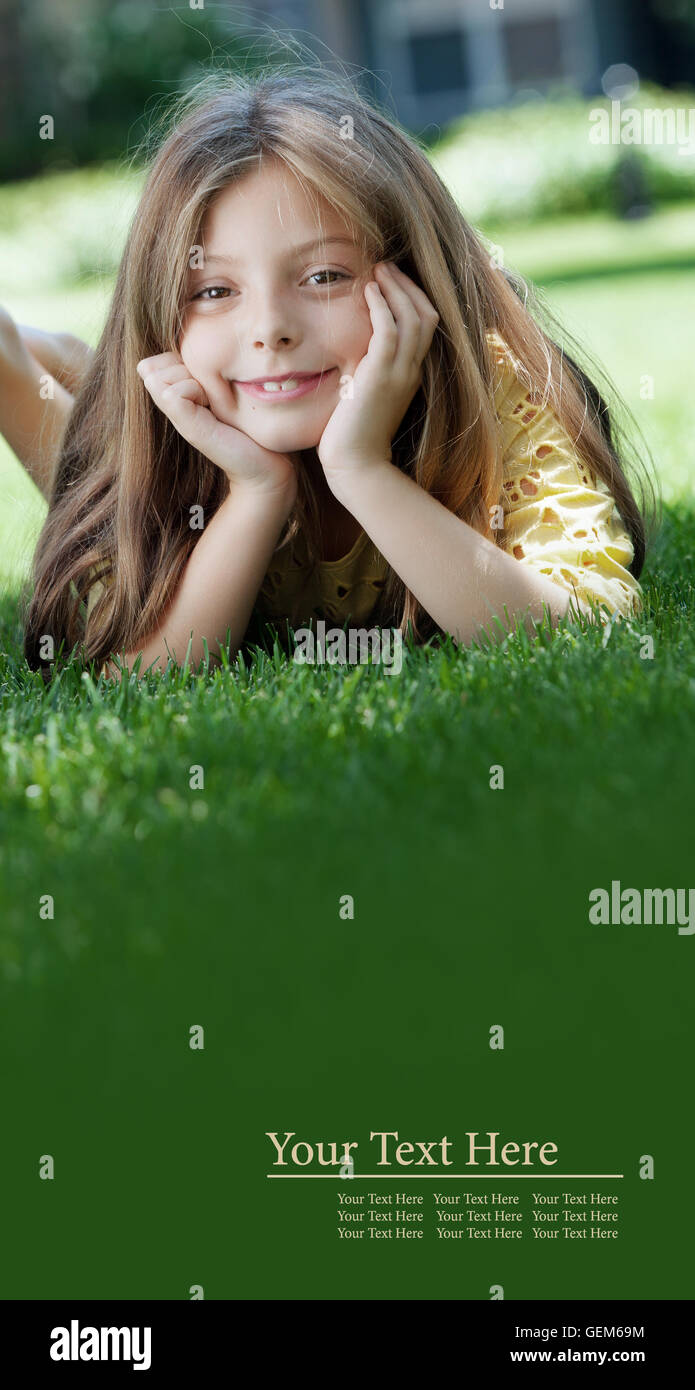 portrait of little girl laying on the grass in summer environment ...