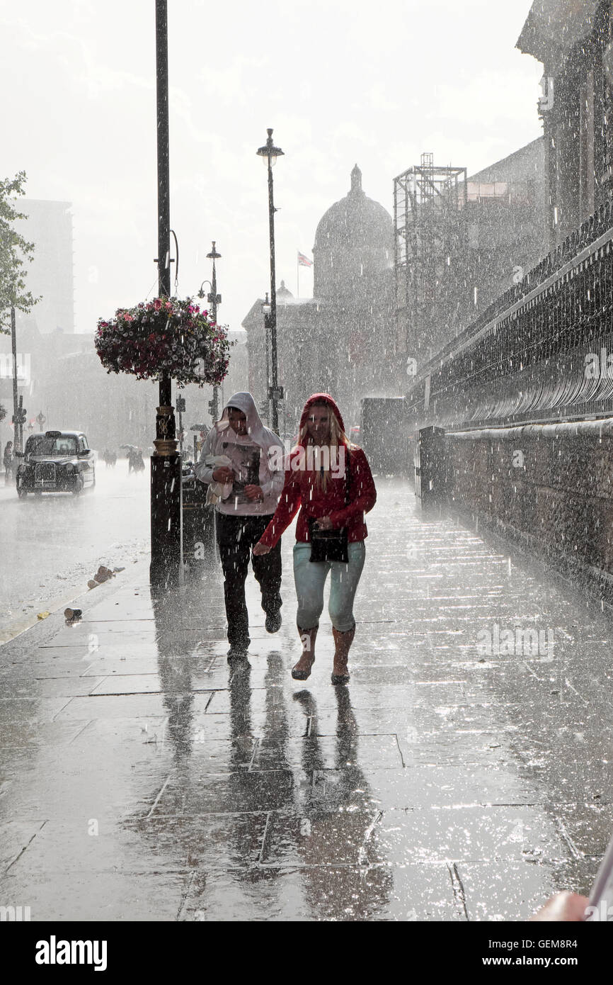 People walking in heavy rain in wet summer 2016 on a street in Charing Cross, London UK  KATHY DEWITT Stock Photo