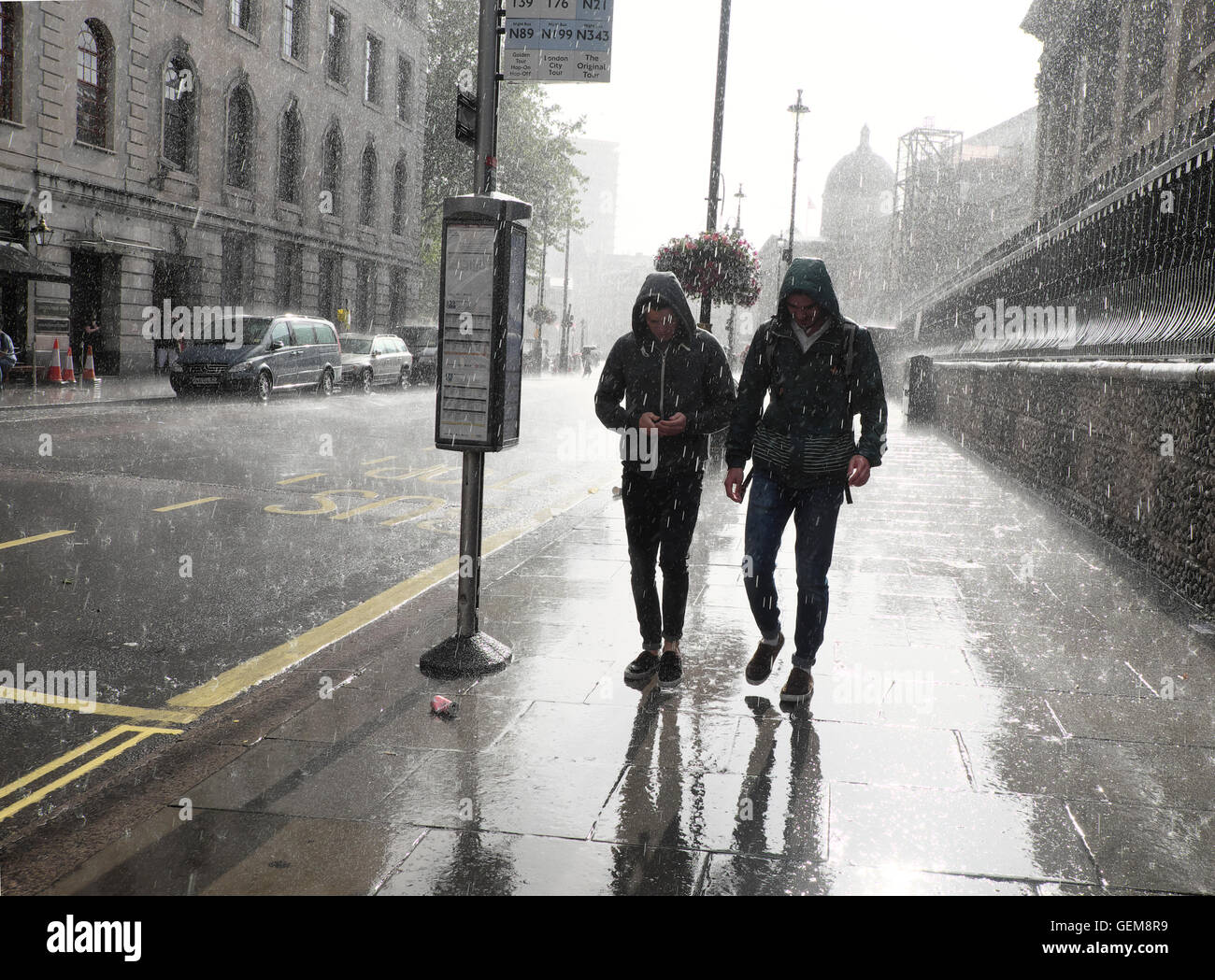 People walking in heavy rain in wet summer 2016 on a street in Charing Cross, London UK  KATHY DEWITT Stock Photo