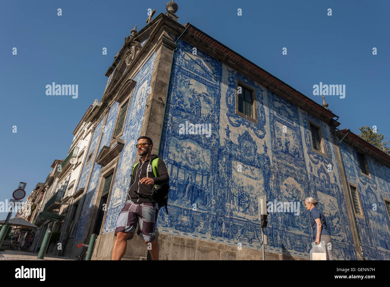 Pedestrians pass beneath traditional Azulejo tiles on the wall of Capela Das Almas (church), on Rua Santa Catarina, Porto Stock Photo