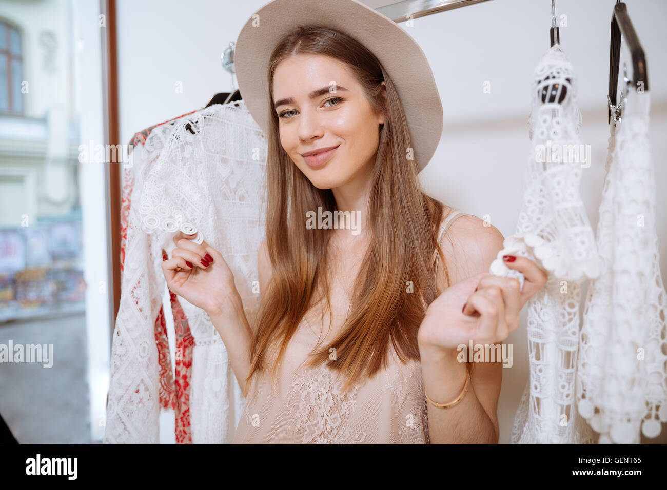 Portrait of cheerful pretty young woman doing shopping in clothing store Stock Photo