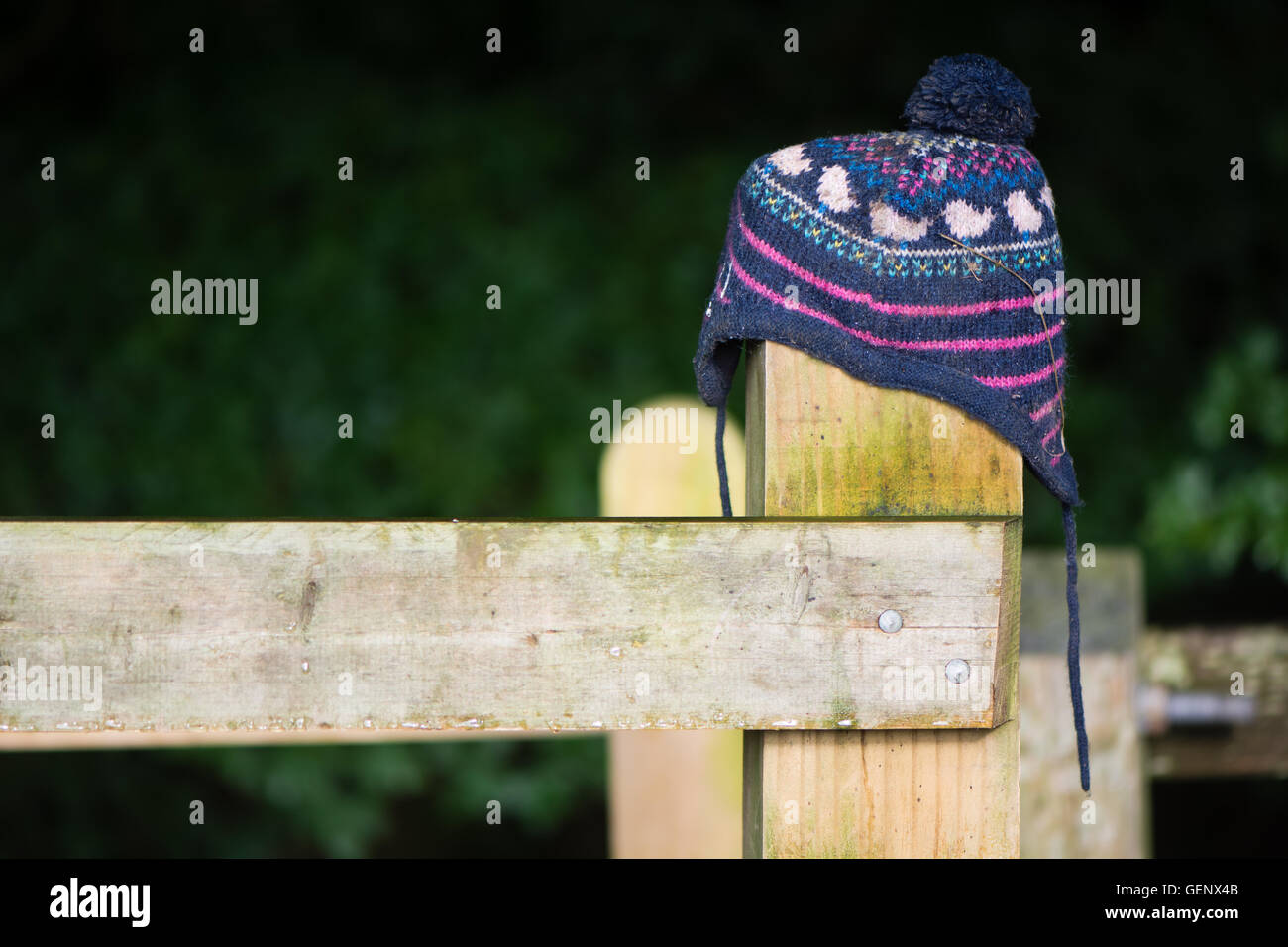 Lost hat on wooden fence post. Wooly child's hat mislaid in countryside placed on gate in hope of being seen by owner Stock Photo
