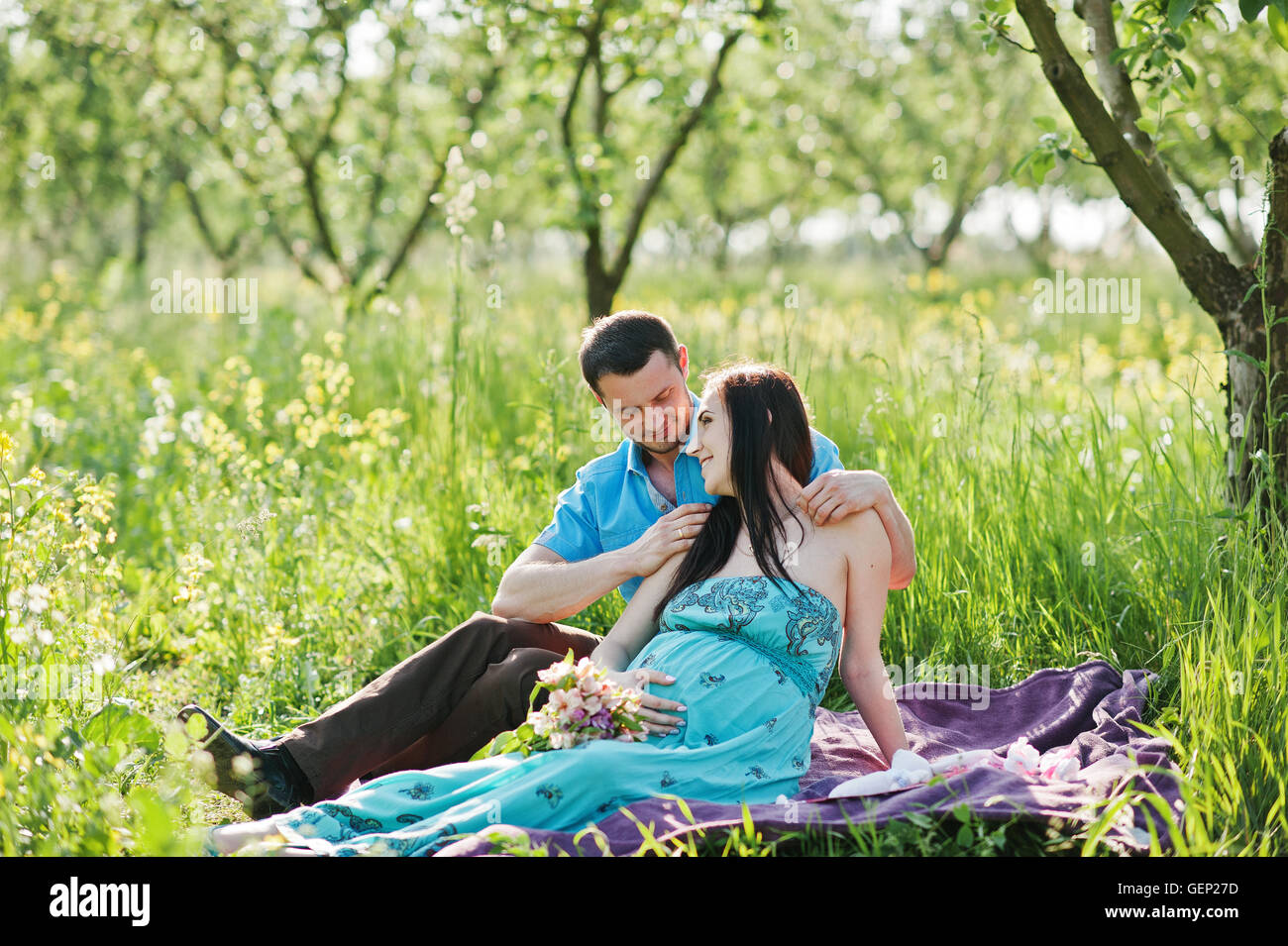 Happy pregnant couple at turquoise dress on the garden Stock Photo - Alamy