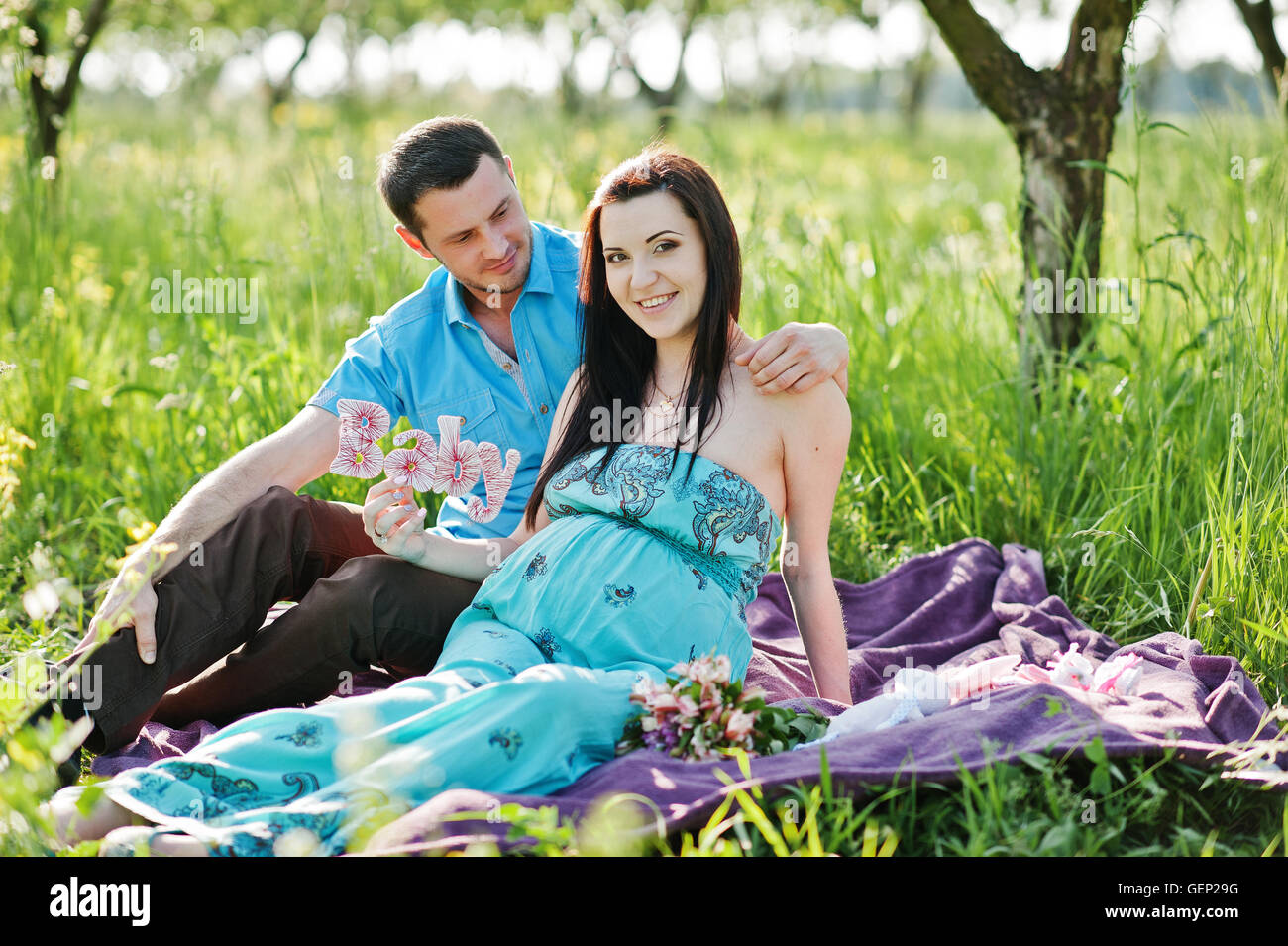 Happy pregnant couple at turquoise dress on the garden Stock Photo - Alamy