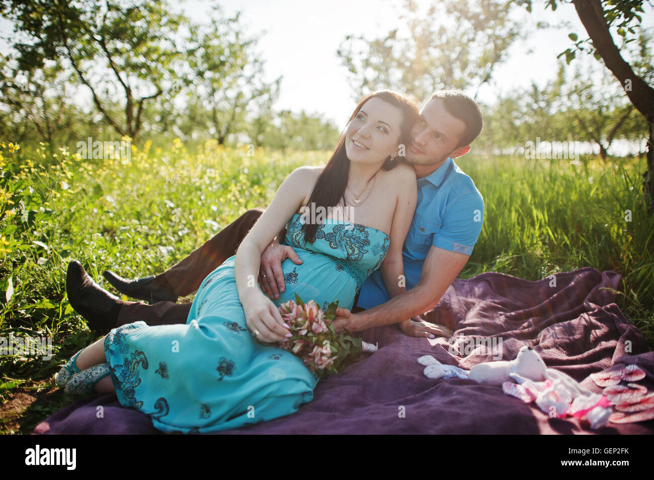 Happy pregnant couple at turquoise dress on the garden Stock Photo - Alamy