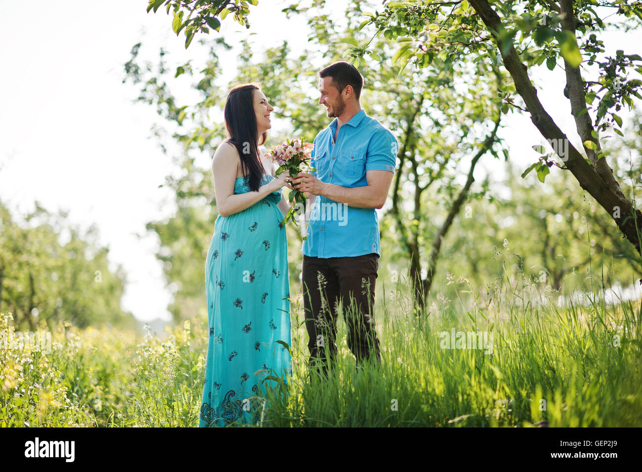Happy pregnant couple at turquoise dress on the garden Stock Photo - Alamy