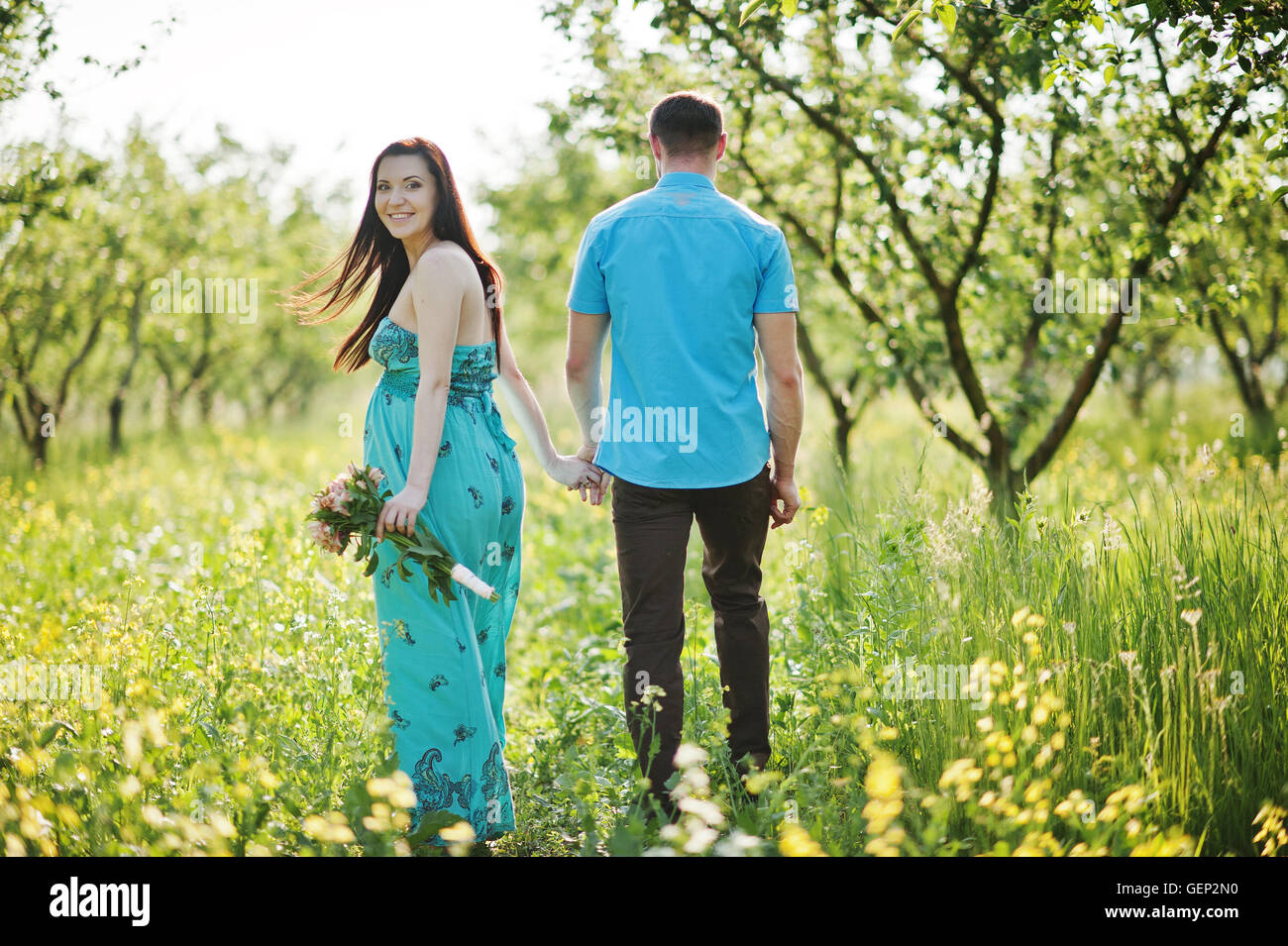 Happy pregnant couple at turquoise dress on the garden Stock Photo - Alamy