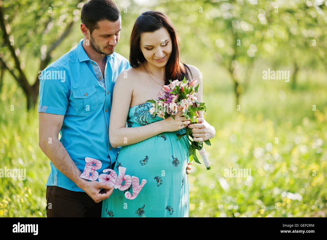 Happy pregnant couple at turquoise dress on the garden Stock Photo - Alamy