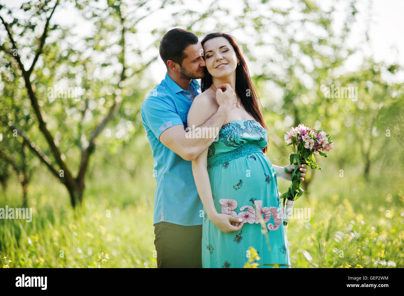 Happy pregnant couple at turquoise dress on the garden Stock Photo - Alamy