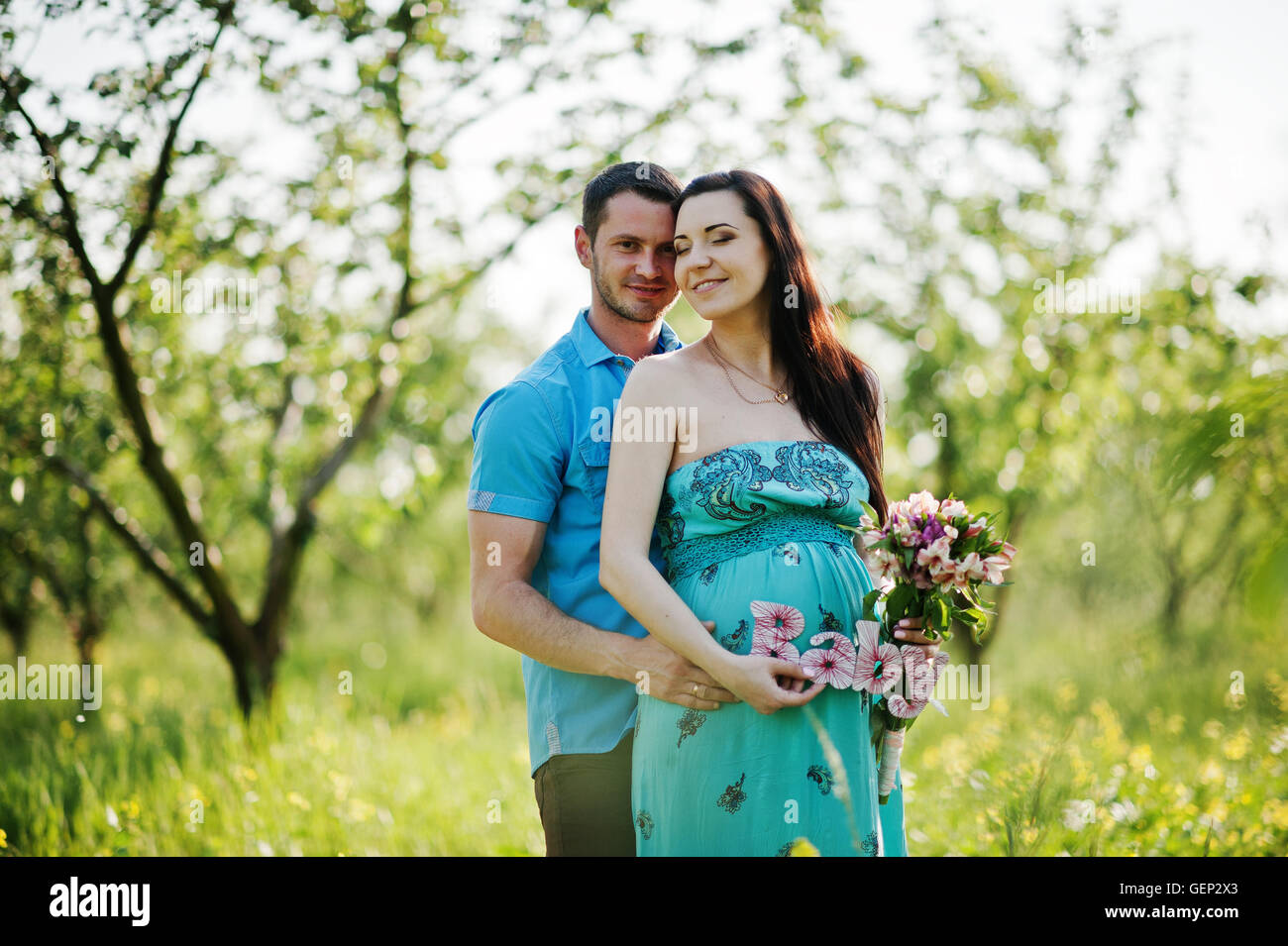 Happy pregnant couple at turquoise dress on the garden Stock Photo - Alamy