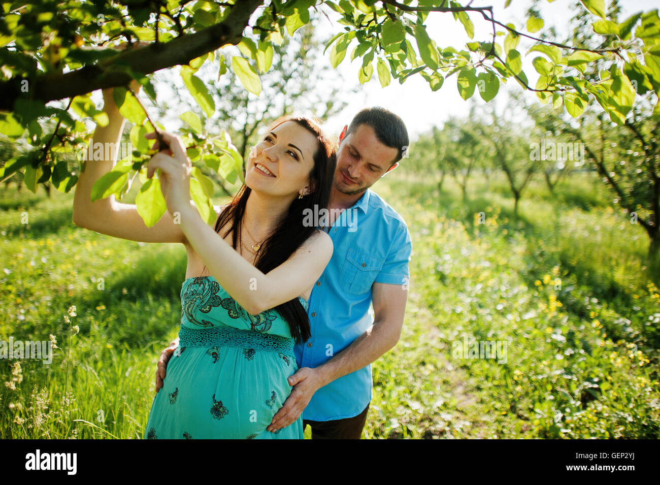 Happy pregnant couple at turquoise dress on the garden Stock Photo - Alamy