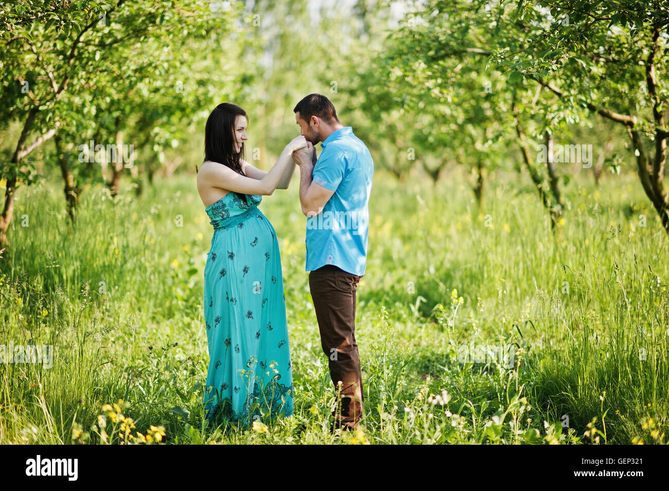 Happy pregnant couple at turquoise dress on the garden Stock Photo - Alamy