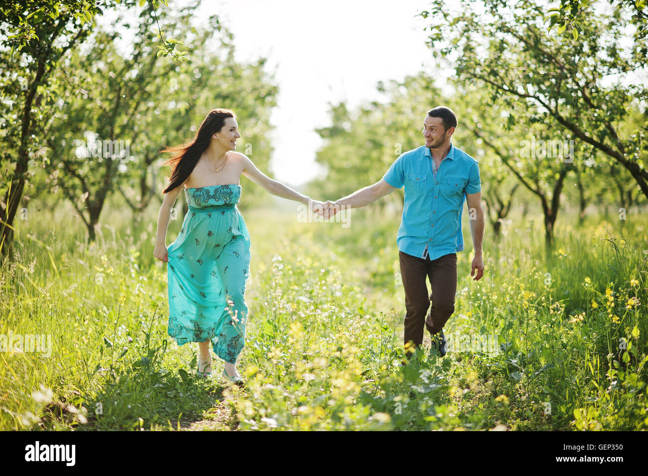 Happy pregnant couple at turquoise dress on the garden Stock Photo - Alamy