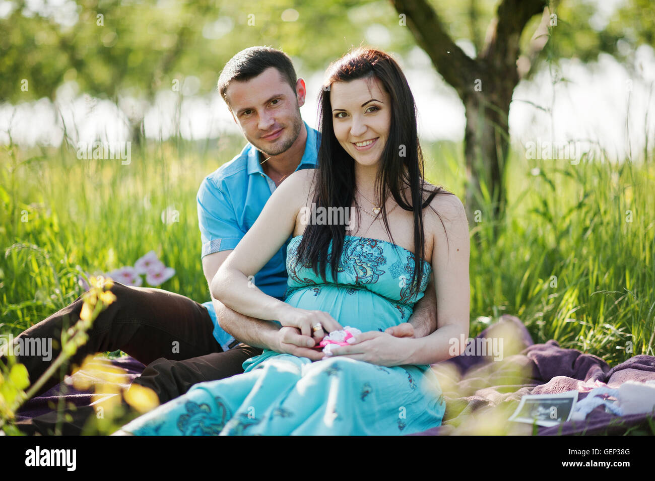 Happy pregnant couple at turquoise dress on the garden Stock Photo - Alamy