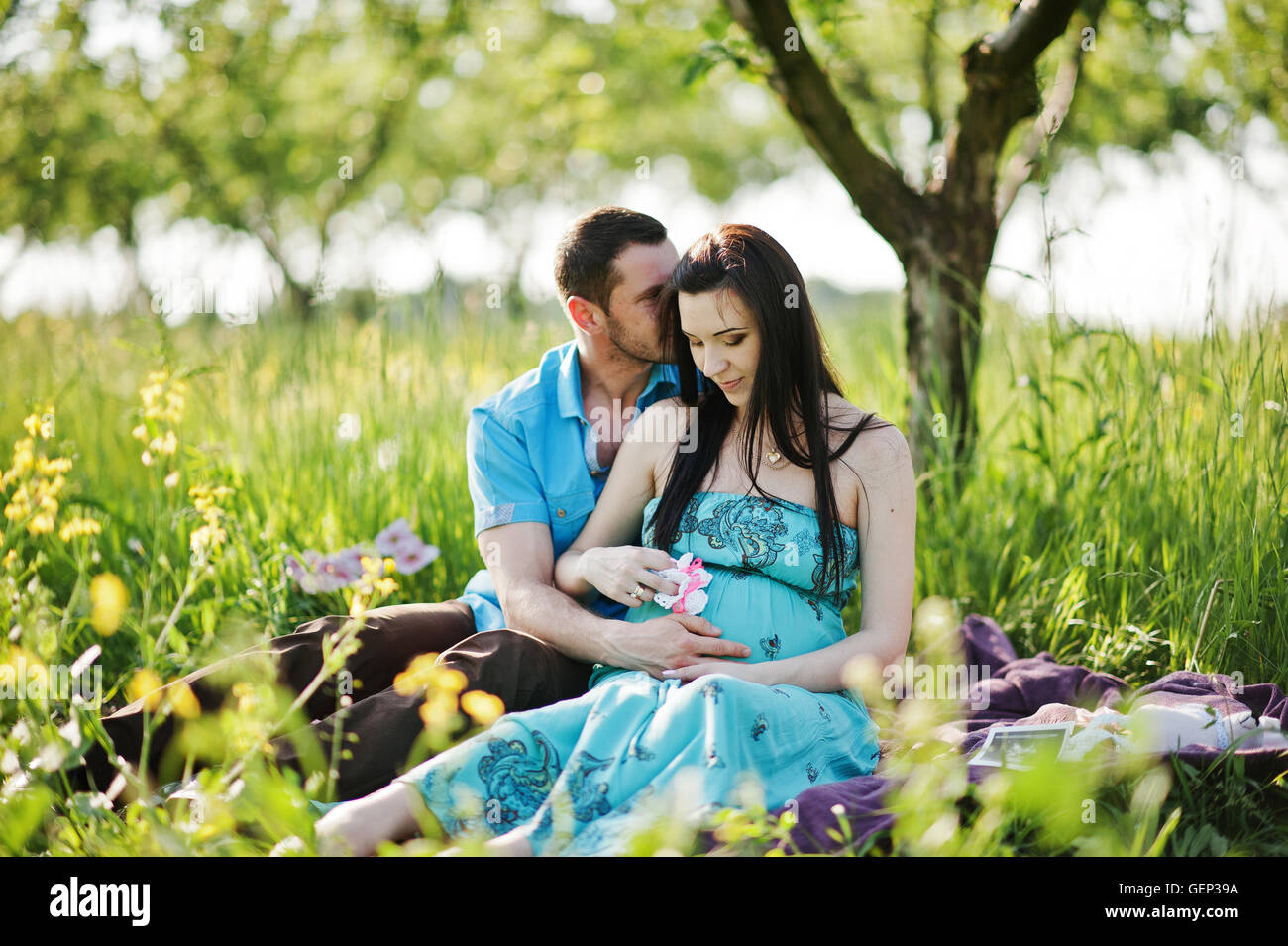 Happy pregnant couple at turquoise dress on the garden Stock Photo - Alamy