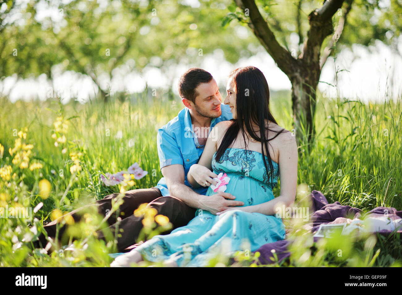 Happy pregnant couple at turquoise dress on the garden Stock Photo - Alamy