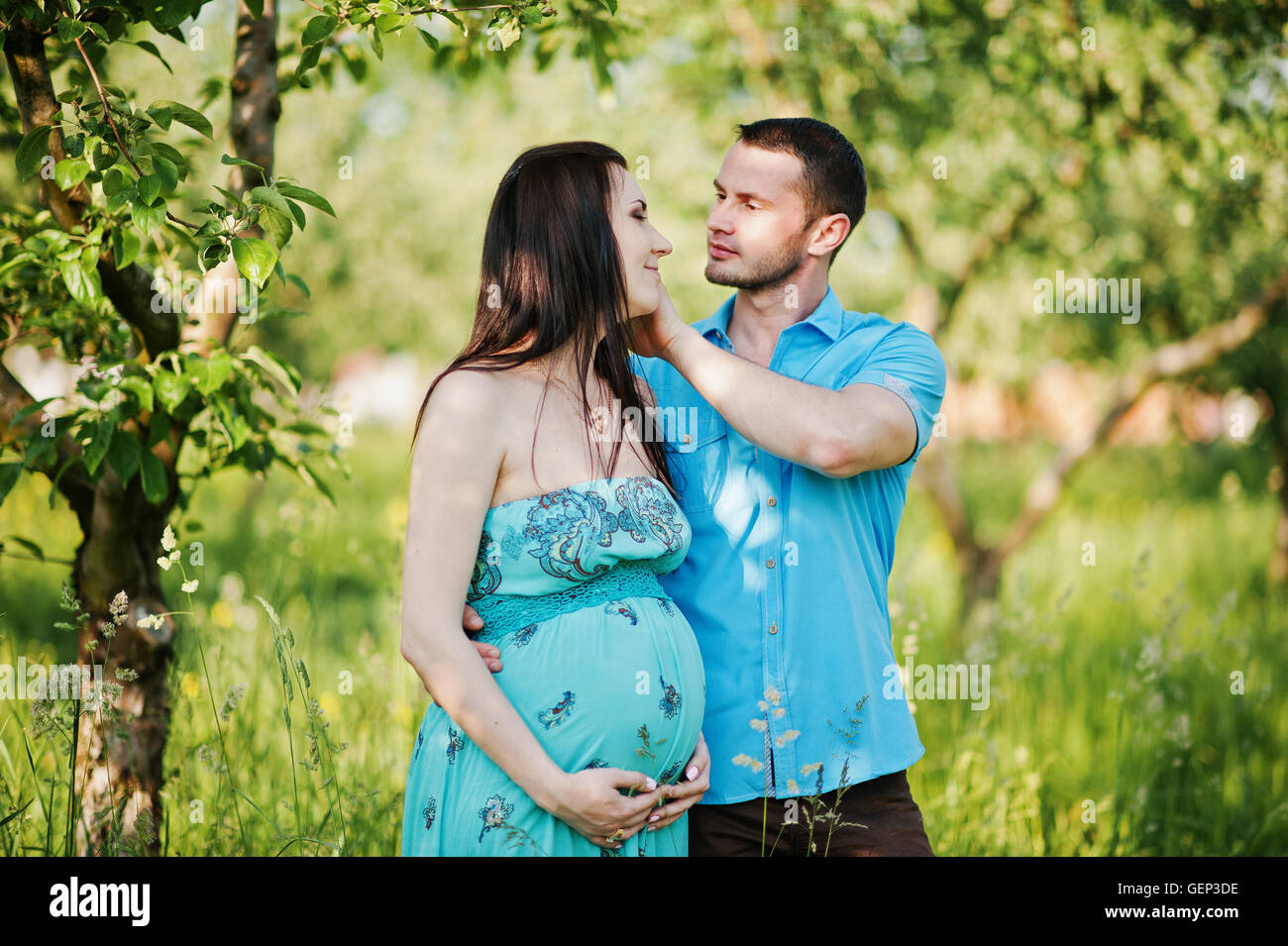 Happy pregnant couple at turquoise dress on the garden Stock Photo - Alamy