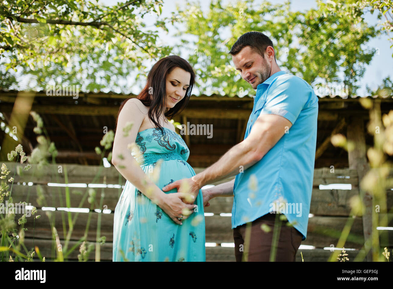Happy pregnant couple at turquoise dress on the garden Stock Photo - Alamy