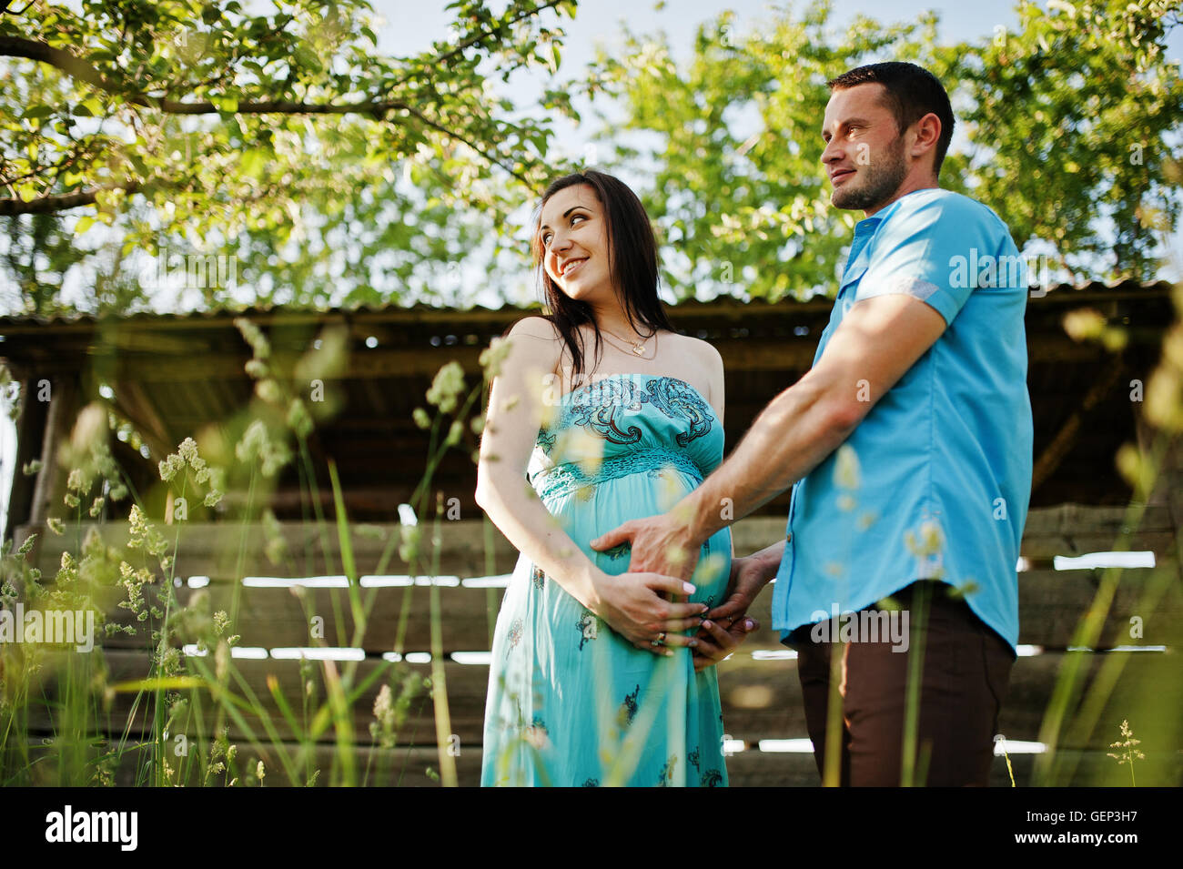 Happy pregnant couple at turquoise dress on the garden Stock Photo - Alamy