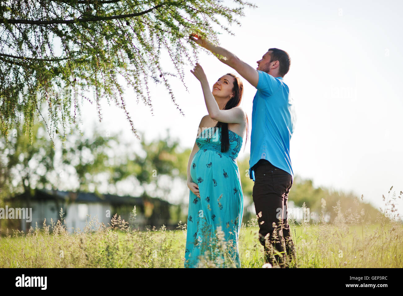 Happy pregnant couple at turquoise dress on the garden Stock Photo - Alamy