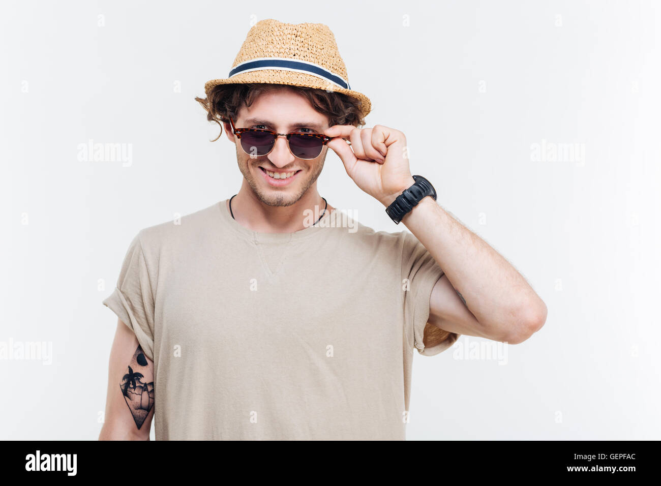 Portrait of a smiling young man in hat taking off his eyeglasses Stock Photo