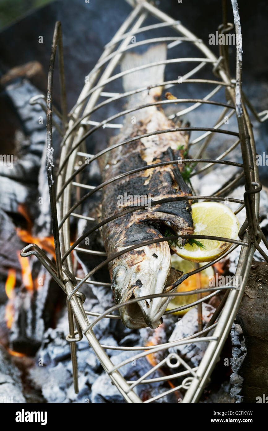 Fish in a fish grill basket over a barbecue. Stock Photo