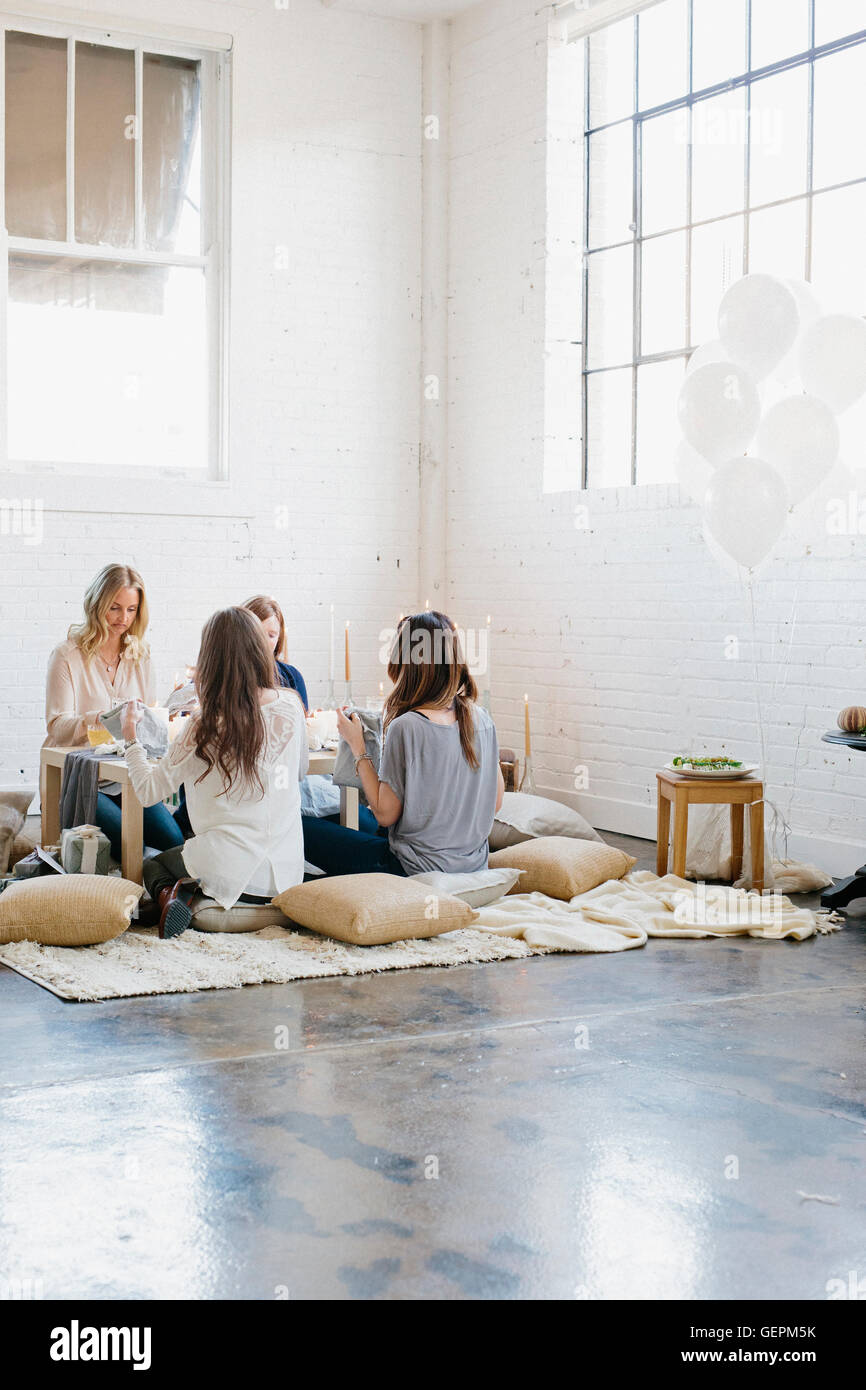 Four women seated at a low table on cushions Stock Photo Alamy