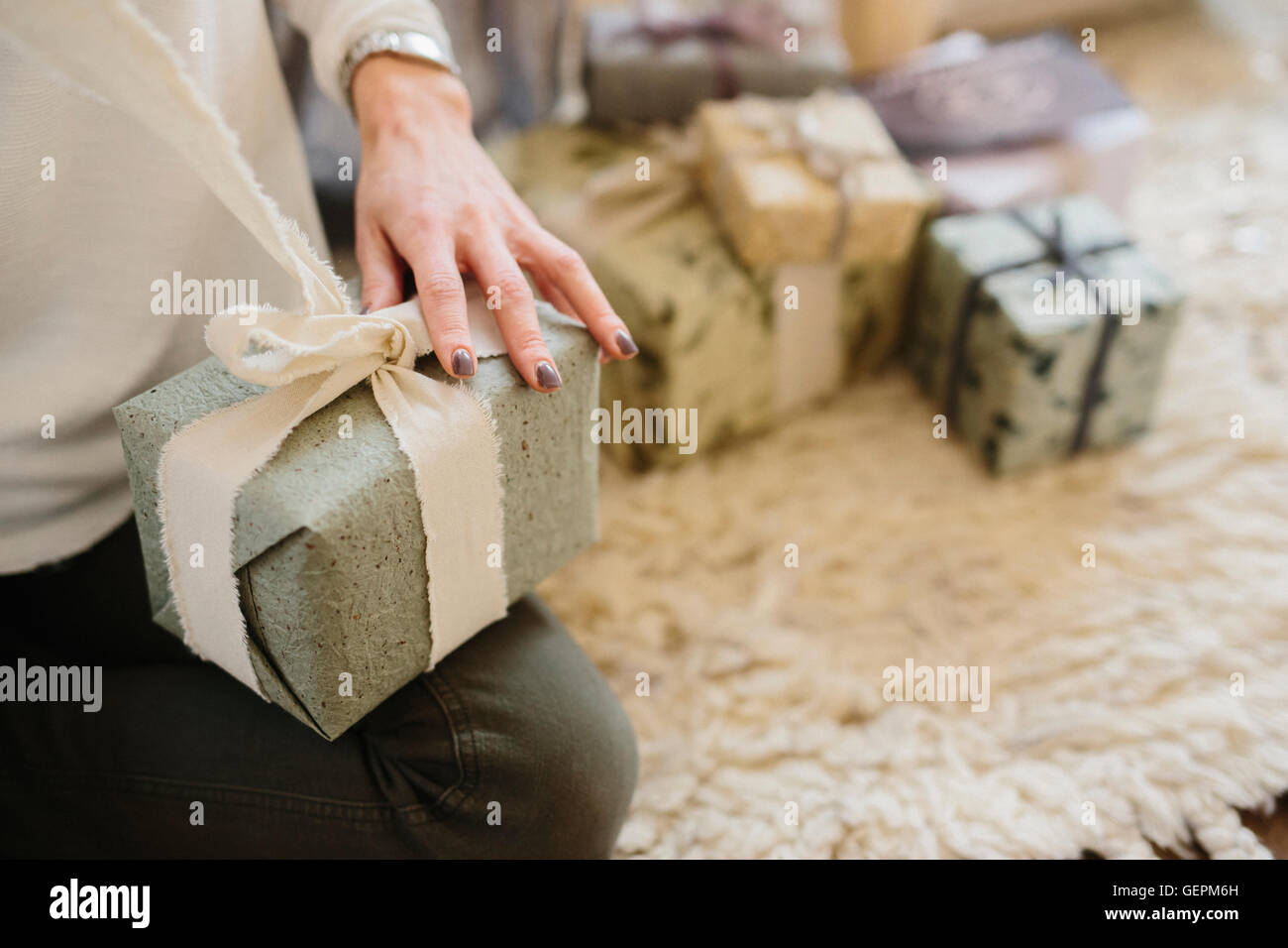 A woman sitting with a pile of wrapped presents. Stock Photo