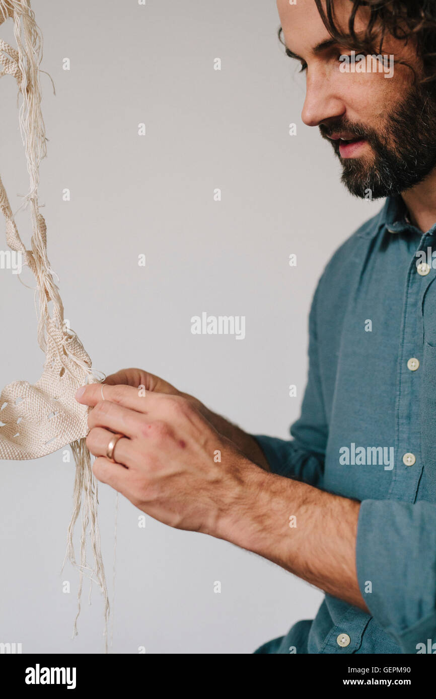 An artist working on an art piece, stitching and weaving with thread. Stock Photo