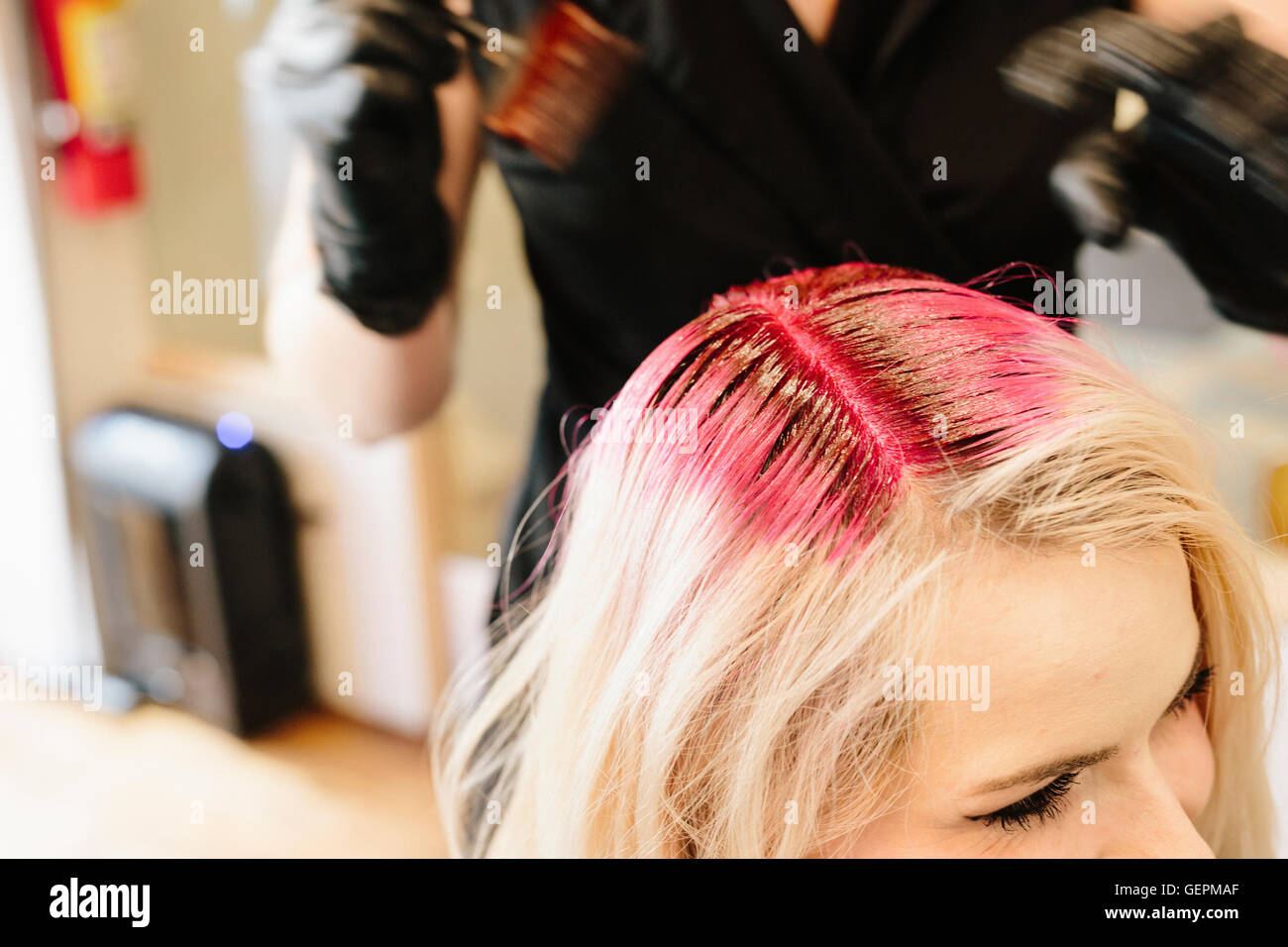 A Hair Colourist In Gloves Applying Red Hair Dye To A Client S Blonde Hair With A Brush Stock Photo Alamy