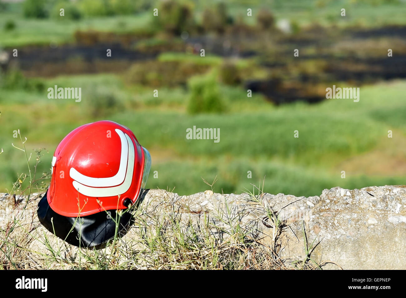 Firefighter helmet on the ground with extinguished fire in background Stock Photo