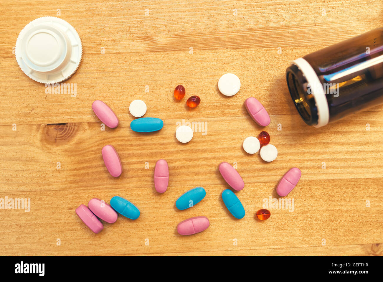 Colorful medical tablets and pills scattered on the desk, top view Stock Photo