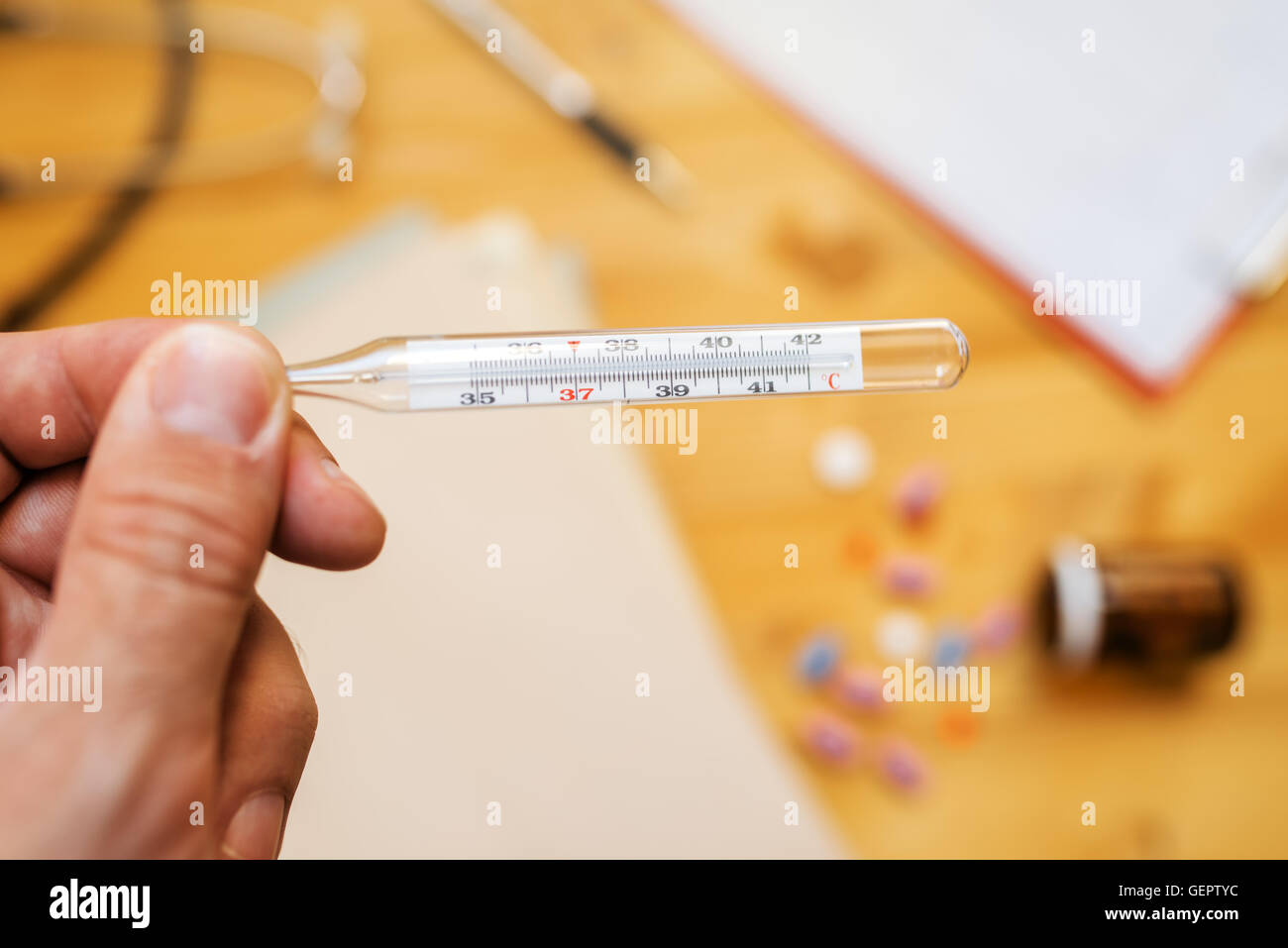 Hand with medical thermometer measuring human body temperature, close