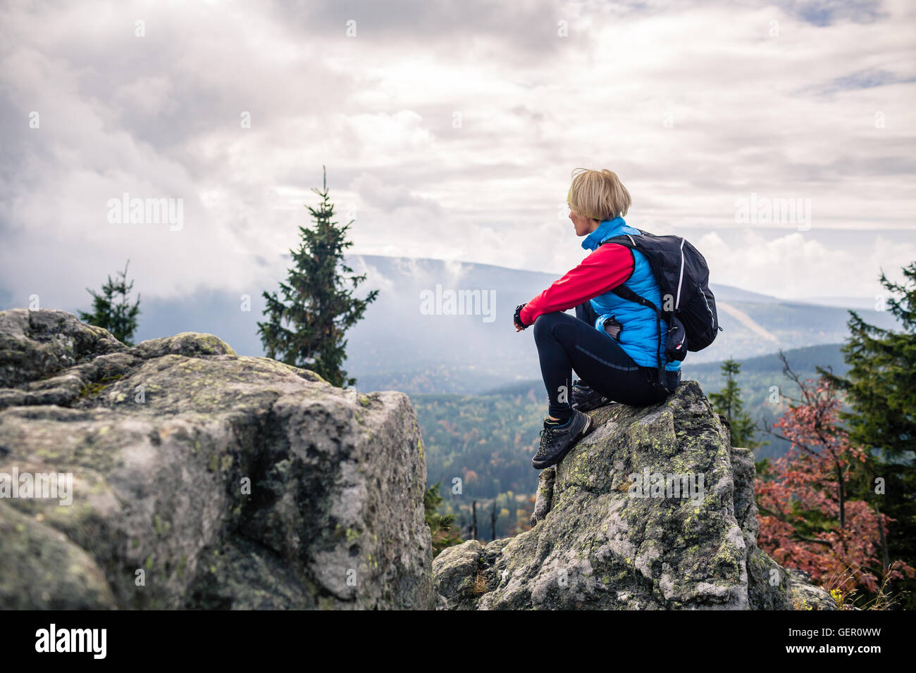 Woman hiking in autumn mountains and woods. Sitting on rock and ...