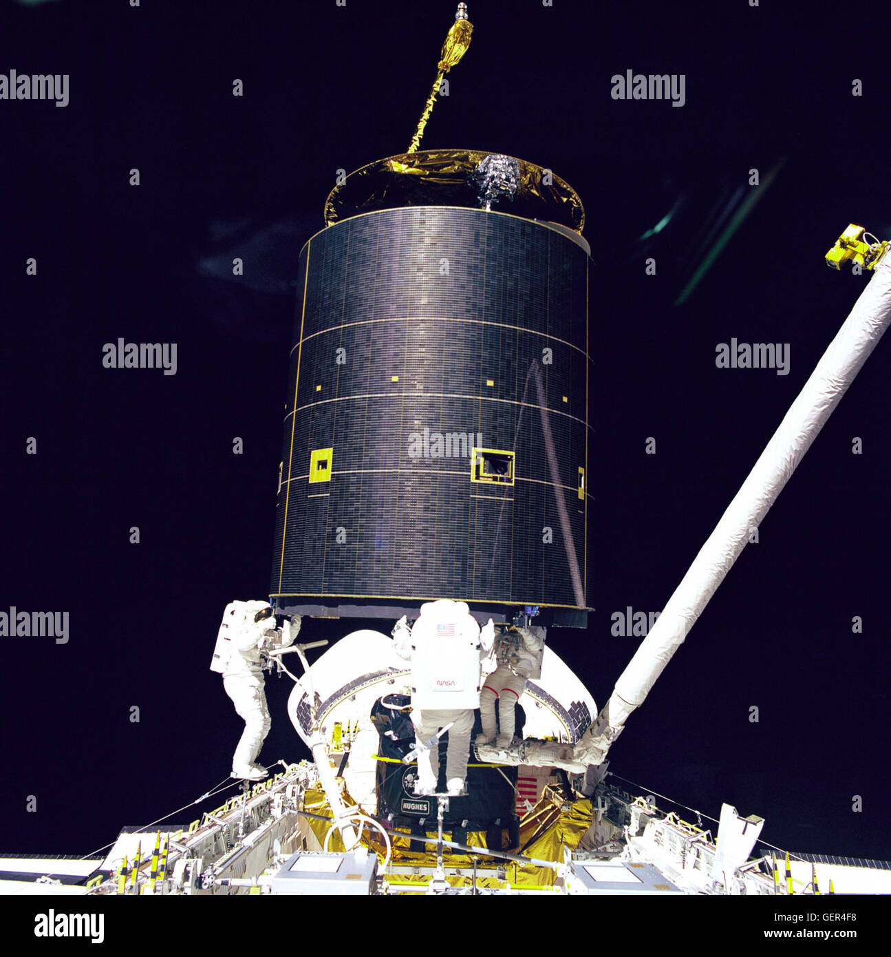 Three crewmembers of mission STS-49 hold onto the 4.5 ton International Telecommunications Organization Satellite (INTELSAT) VI after a six- handed &quot;capture&quot; was made minutes earlier during the mission's third extravehicular activity (EVA). From left to right: Mission Specialists Richard J. Hieb, Thomas D. Akers, and Pierre J. Thuot. The three prepare to attach the capture bar which is tethered to Hieb. Thuot is positioned on the Remote Manipulator System (RMS) arm, from which he had made two earlier unsuccessful grapple attempts on two- person EVA sessions. Ground controllers and cr Stock Photo