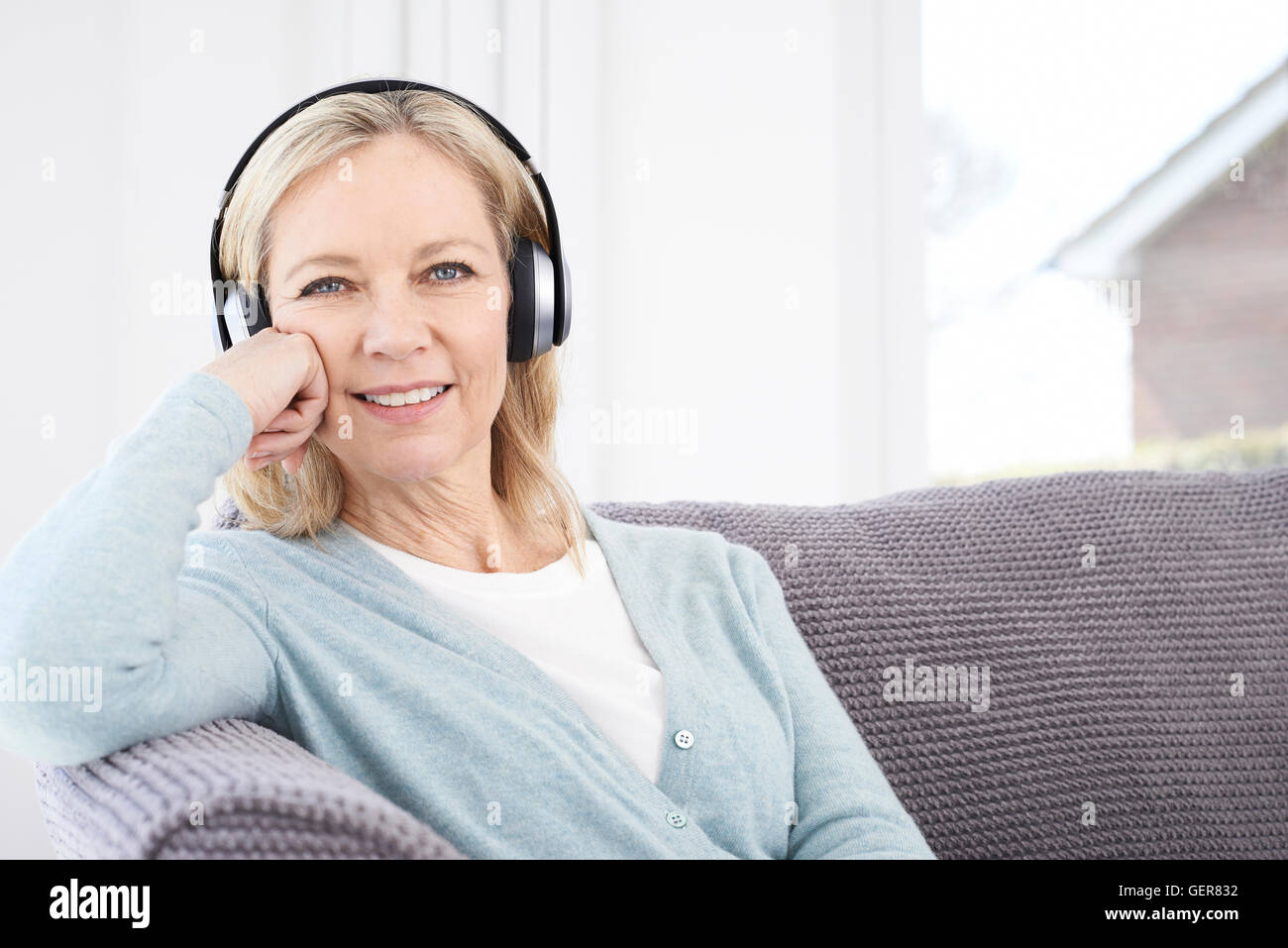 Mature Woman Listening To Music On Wireless Headphones Stock Photo - Alamy